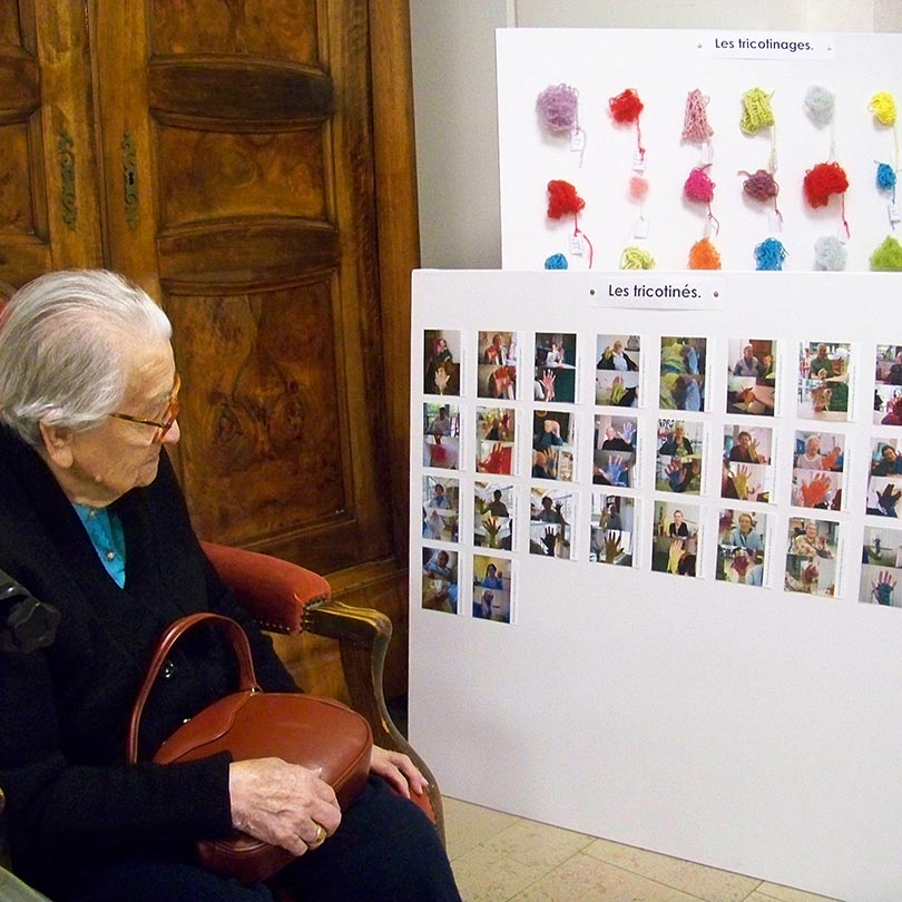 Tricotinage, Colmar. Participante regardant les tableaux de tricotins. Art participatif. Viviane Rabaud
