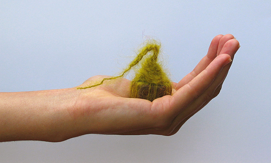 Boulainerie Viviane Rabaud. Textile. Main portrant un ecrou avec laine mohair verte.