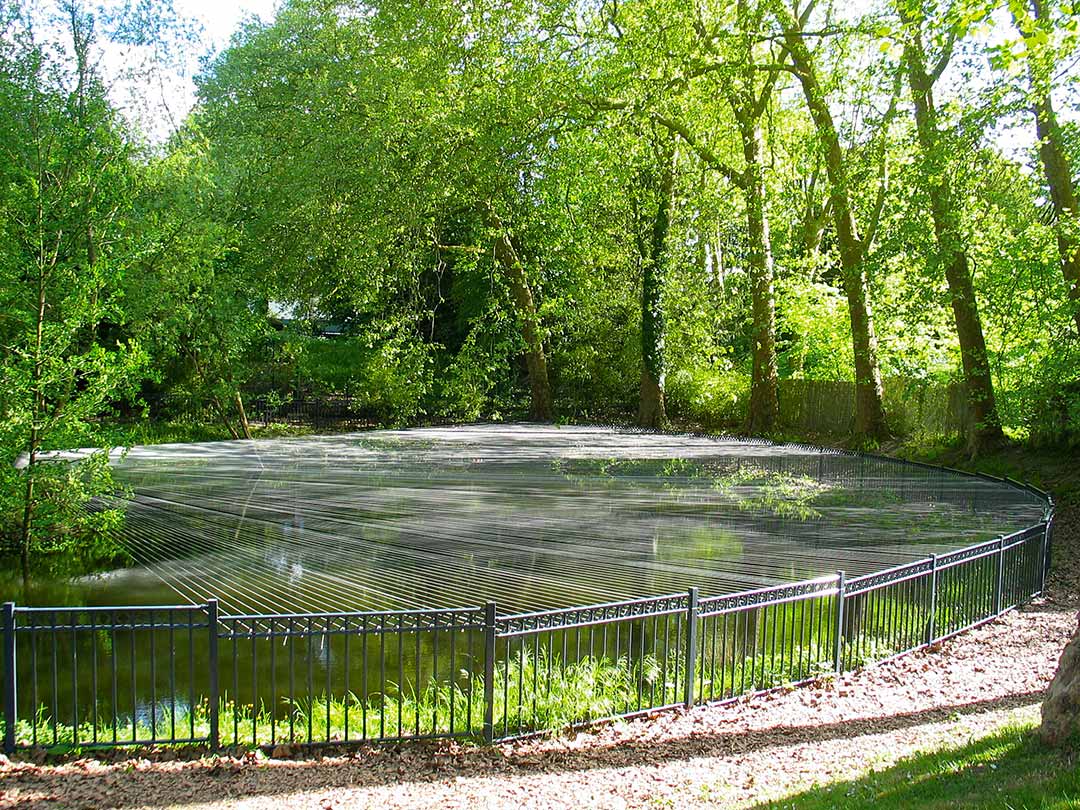 libération du tapis, parc de l'oseraie, les mureaux. Installation filaire in-situ, fils de chaine tendus entre une ile et les rembardes de l'étang. Art participatif, Viviane Rabaud