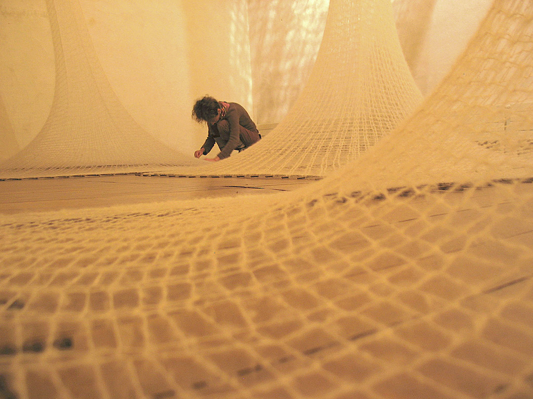Installation Textiile. Laine Mohair blanche tricotinée sur treillis de fer à béton. Artiste au travail.