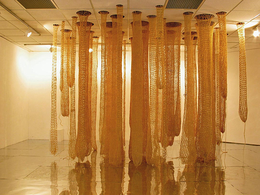 Installation textile, Viviane Rabaud - Centre Art le Colombier, Rennes. Tricotins géants de ficelle sisal descendant du plafond. Sol en plaques d'acier brillantes.