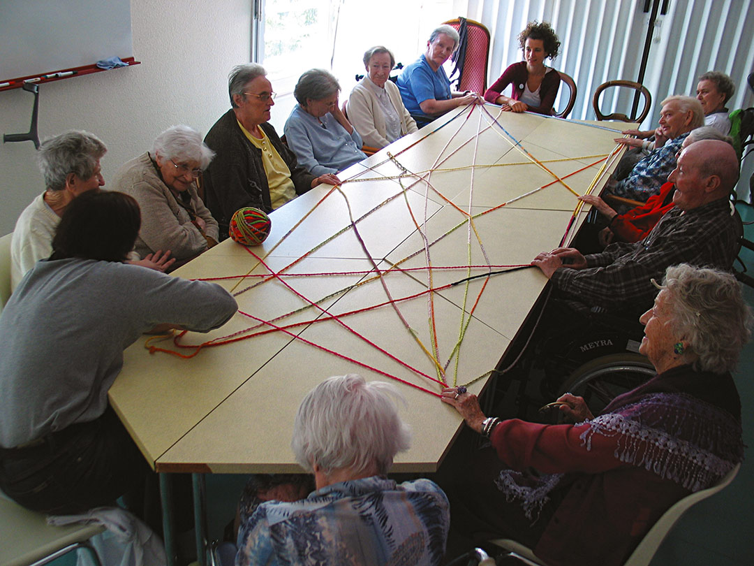 Tricotinage. Groupe de discussion se passant la boule de tricotin. Art participatif. Viviane Rabaud. Colmar.