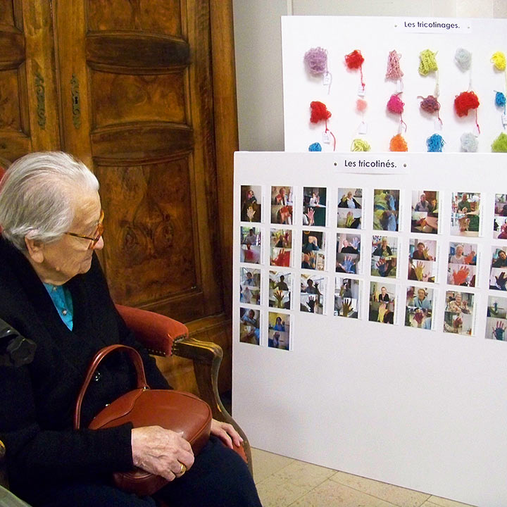 Tricotinage, Colmar. Participante regardant les tableaux de tricotins. Art participatif. Viviane Rabaud