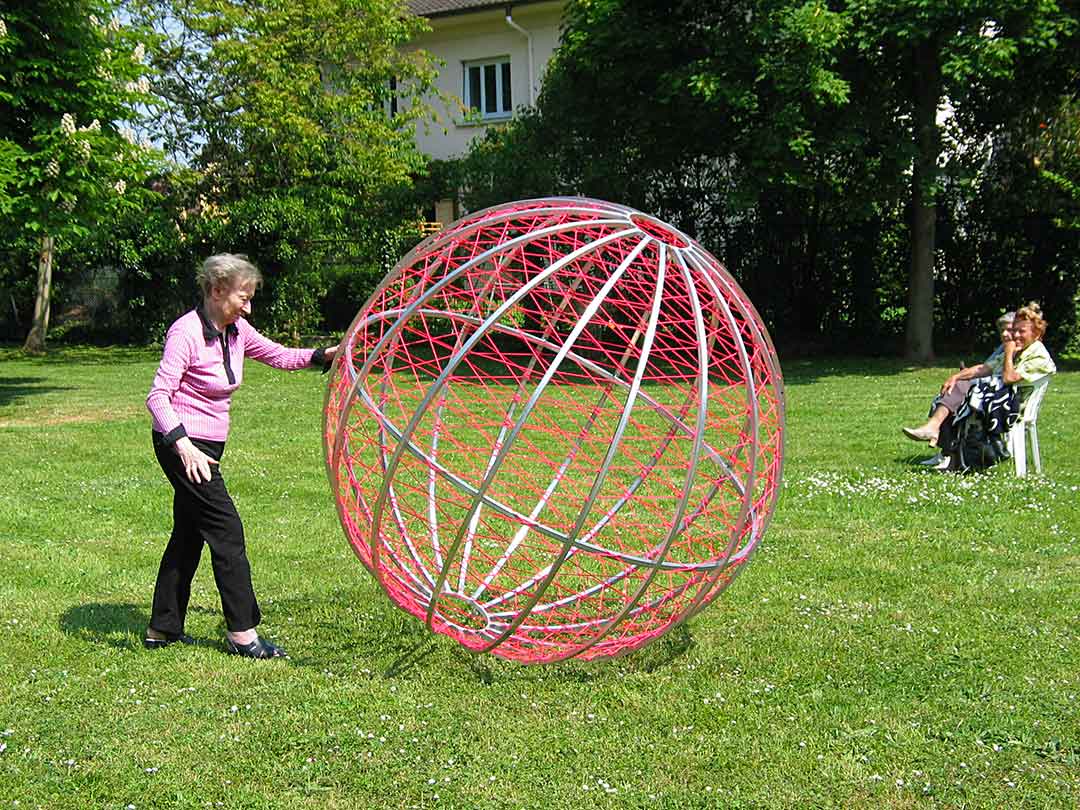 Participante poussant une sphère en aluminium recouverte de drisse de couleur rose. Viviane Rabaud, Oeuvre pérene, Art participatif, Colmar